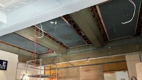 Ipswich Borough Council A view of the theatre's ceiling which has been removed. Wires hang from the ceiling and some lights can be seen.
