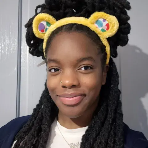 Nyarai in a selfie, smiling at the camera and wearing Children In Need ears