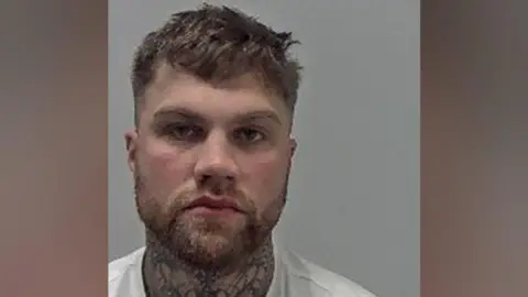 West Mercia Police A police mug shot of Ryan Twardun, who has short dark hair and facial hair. He has tattoos on his neck