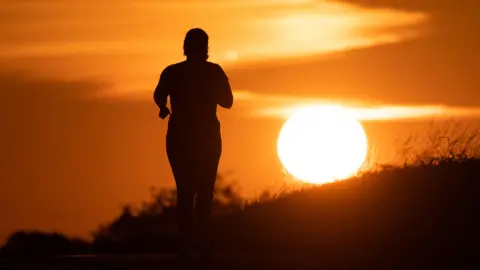 A woman jogs along a path as the sun rises in Frankfurt am Main, Germany, 09 July 2026. 