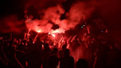 PSG supporters release flares during clashes with police in Paris.