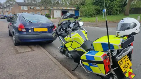 Hertfordshire Police A police bike parked next to a car on a residential estate
