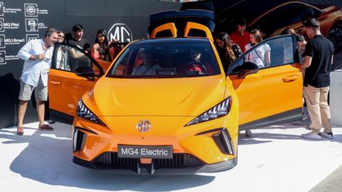 Visitors look at MG4 on display at electric vehicle fair in Spain.