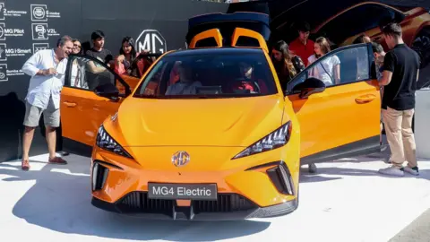 Visitors look at MG4 on display at electric vehicle fair in Spain.