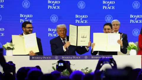 Reuters Bahrain's Minister of the Prime Minister’s Court Shaikh Isa bin Salman bin Hamad Al Khalifa, U.S. President Donald Trump and Morocco's Foreign Minister Nasser Bourita hold signed Charter of the Board of Peace, as the takes part in a charter announcement for his Board of Peace initiative aimed at resolving global conflicts, alongside the 56th annual World Economic Forum (WEF), in Davos, Switzerland, January 22, 2026.