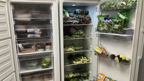 BBC A ample  escaped  lasting  fridge afloat   stocked with vegetables specified  arsenic  outpouring  onions, avacado, brussel sprouts and lettuce.  Its doors are open.  Beside the fridge is simply a ample  freezer conception  afloat  of frozen meat, vegetarian and vegan produce.