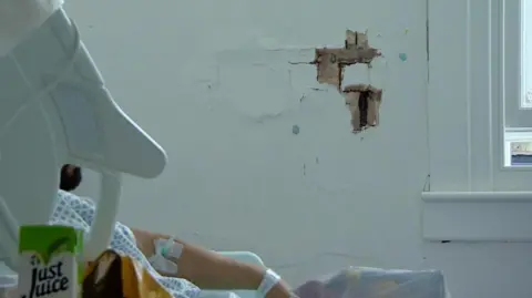 A hole in the wall next to a patient in bed at St Mary's Hospital in London