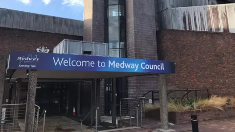 The entrance to Medway Council’s Gun Wharf building, showing a blue “Welcome to Medway Council” sign, brick exterior and metal‑clad upper sections.