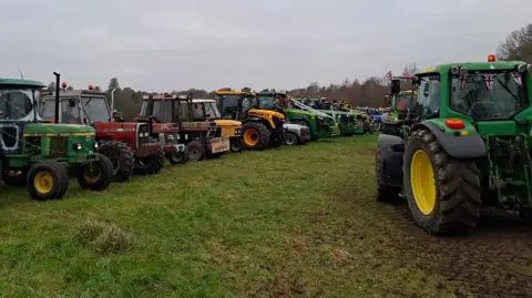 Alex Drake A row of tractors on a field 
