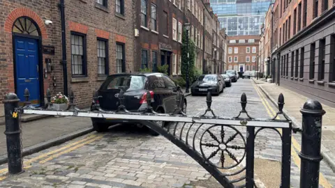 A general view of a street with a metal fence at one end that blocks traffic. 