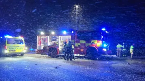 Emergency service staff stand by a fire truck in the snow