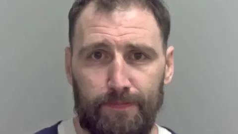 Norfolk Police Police custody image of Adam Barnard who has a beard.