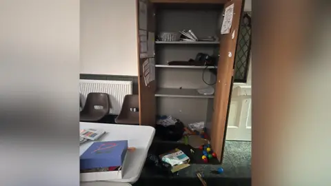 Ben Pickering Cupboards wide open with items scattered messily over the floor. 