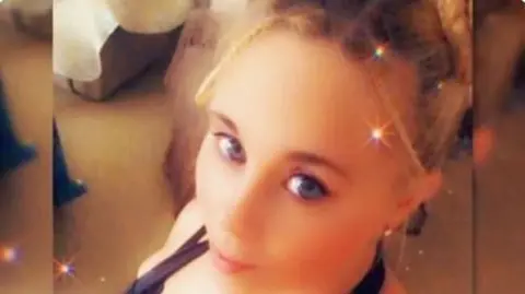 Aimee Betro/Instagram woman with dark blond hair and blue eyes looks at the camera. The picture is softened with a filter that also added stars to it.