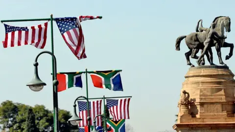 The South African and American flags of the AFP flutter from the flag posts for the union buildings in the capital of South Africa, Pretoria. On the left, a monument with a horse marks the dates of World War II.