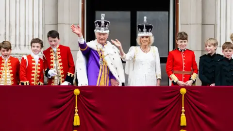 Getty Images The King and Queen dressed in coronation robes appear on the Buckingham Palace balcony alongside pageboys - including the future king George. 