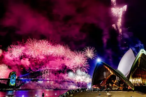 SAEED KHAN/AFP Kembang api menerangi langit tengah malam di atas Jembatan Pelabuhan Sydney dan Gedung Opera Sydney saat perayaan Tahun Baru 2025 di Sydney pada 1 Januari 2025.