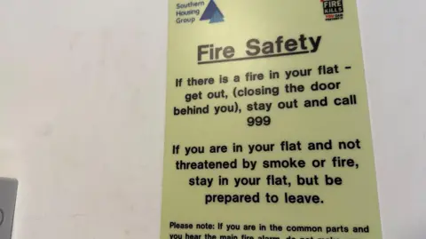 A yellow fire safety sign with black text.