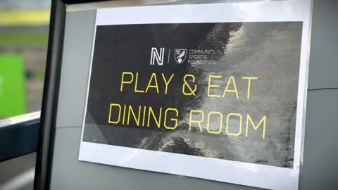Cameron Noble/BBC A black sign with yellow writing which says 'play and eat dining room'