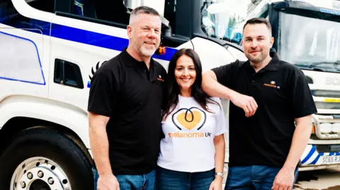 RJC Plant Services Ltd Chris Jackson, co-director, Zena Jackson, office manager, and John Harrison, co-director, stand in front of a lorry and wear Melanoma UK t-shirts