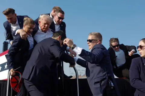 Getty Images Republican presidential candidate former President Donald Trump is rushed offstage by U.S. Secret Service agents after being grazed by a bullet during a rally on July 13, 2024 in Butler, Pennsylvania. 