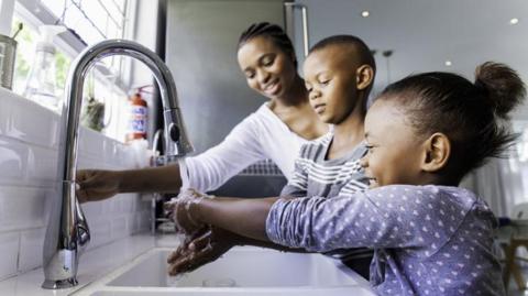 Stock photo of family washing hands in the kitchen sink