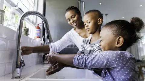 Getty Images Stock photo of family washing hands in the kitchen sink