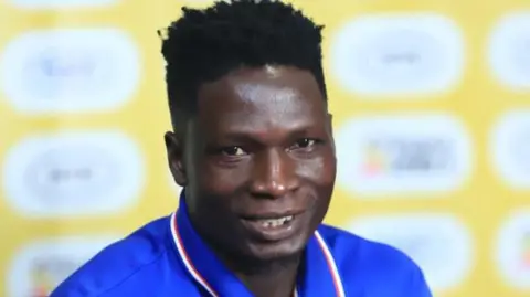 A close-up of David Owori at a press conference