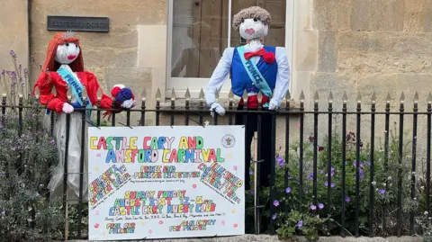 Two scarecrows, one male wearing a sash saying prince and one female wearing a sash saying princess