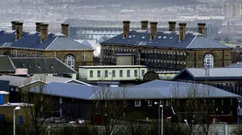 PA Media A view of Barlinnie Prison showing the roofs of several buildings, with homes further in the background