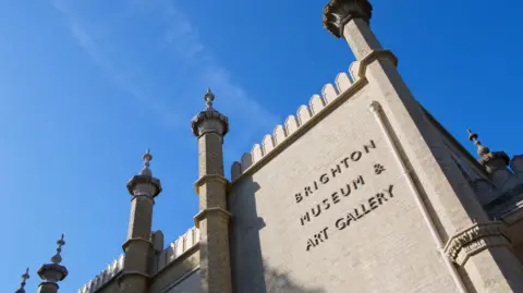 An old building on a sunny day. On the side is written Brighton Museum and Art Gallery. 