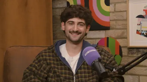 Italian Bach sitting in the You About? podcast studio, smiling at the camera