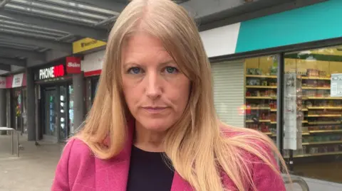 Donna jones wearing black and pink and stood in the high street