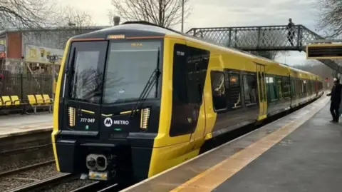 A black and yellow Merseyrail train at a station