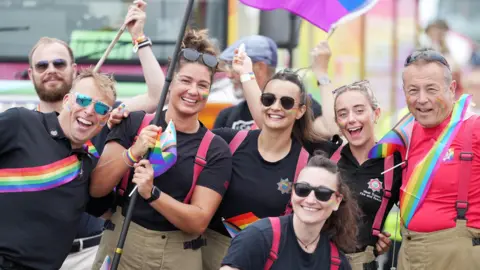 Eddie Mitchell Six people from Crews from West Sussex Fire and Rescue Service in the parade. Five in black shirts with a rainbow stripe, one man on the right with a red shirt and rainbow stripe