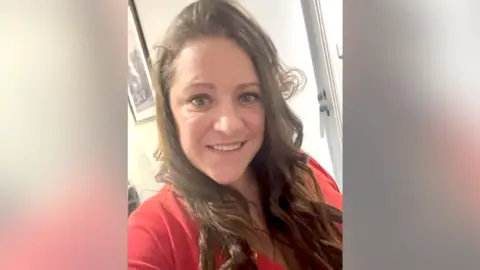 Supplied A close up of Amanda's face. She is smiling and wearing a red top.