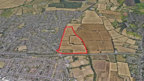 Google Earth A satellite image of houses and a red area marked out where potential homes would be. 