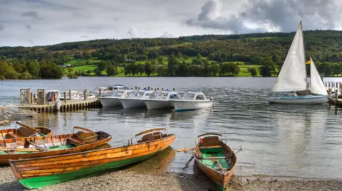 Library image of small boats moored along the shoreline at Coniston Water. 