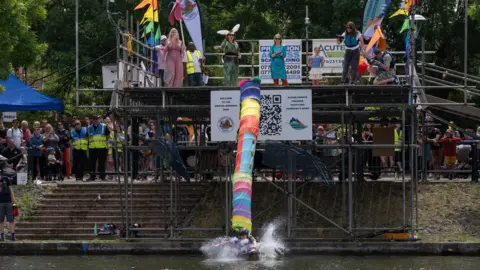 Robert Browne Person attached to rainbow shoot attached to them splashing in the water.