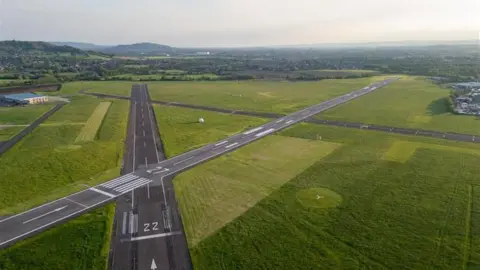 Aerial photo of Gloucestershire Airport. The runways can be seen and the wider landscape shows fields and nature.