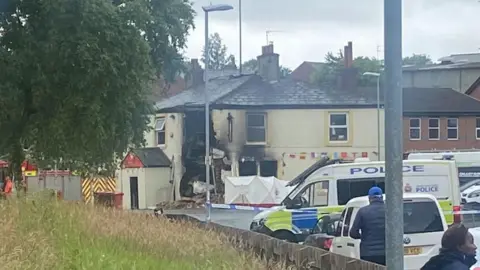 People gather outside the police cordon, with the damaged pub in the background