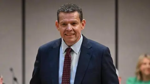 Rhun ap Iorwerth wearing a suit, with a red tie 