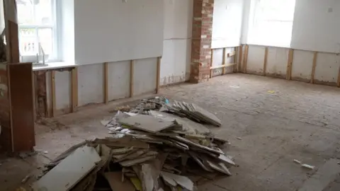 Jamie Niblock/BBC The main reception area at Debenham Veterinary Practice. The floor and walls are bare. In the middle, there is a pile of plaster board. 