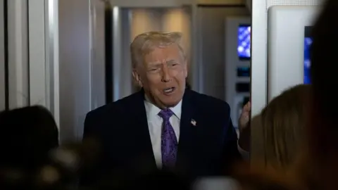 US President Donald Trump wears navy suit and purple tie as he speaks to reporters