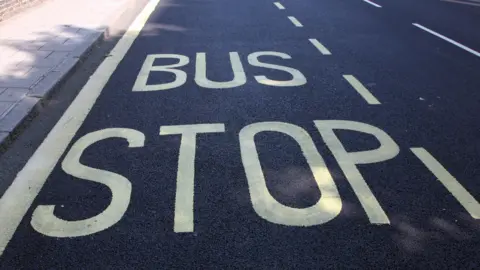 A bus stop sign painting on a road. The large letters are yellow and stand out against the dark tarmac. 