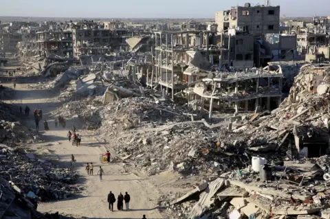 Reuters Displaced Palestinians walk past the rubble as they attempt to return to their homes in northern Gaza, on the day the ceasefire.