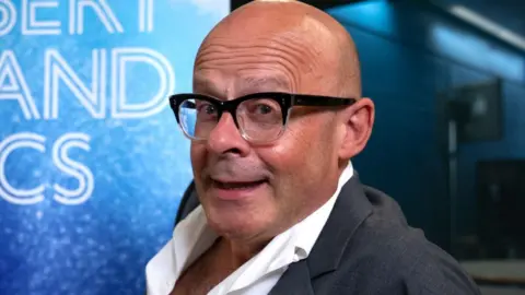 Harry Hill in the Desert Island Discs studio, wearing a suit with an open-collar shirt