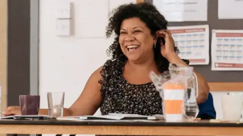 Bristol Old Vic Nancy Medina sitting at a desk.