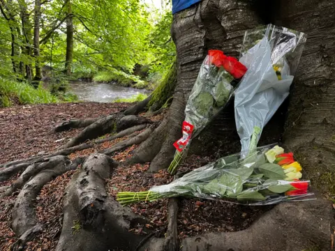 Flowers left next to a tree near where Jordan Moore was found