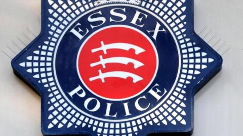 A star-shaped blue badge with "Essex Police" written either side of a red circle